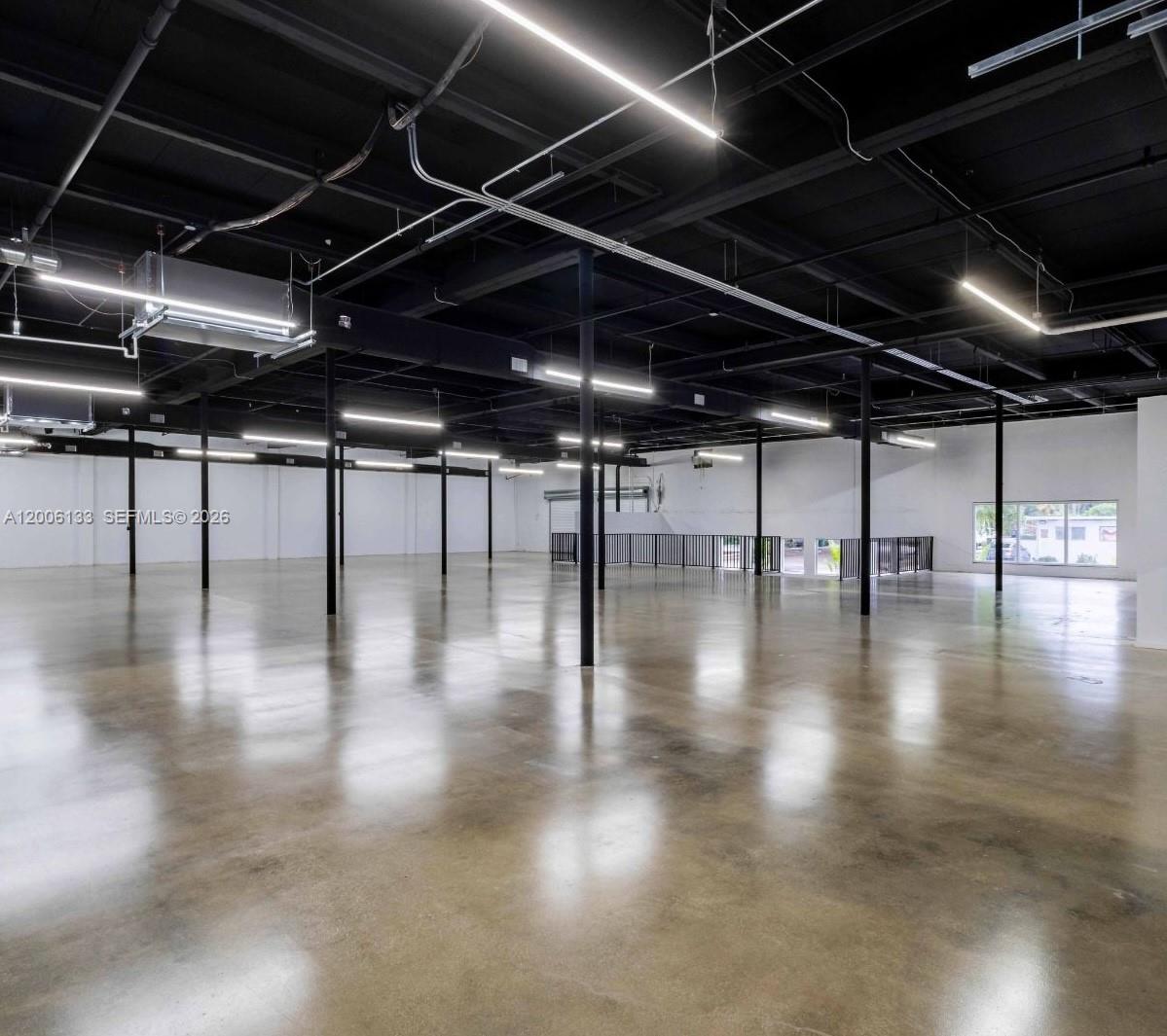 An expansive, open-plan commercial space features polished concrete floors, exposed black ceilings, and linear lighting — 6800 NE 4th Ct, Miami FL 33138, MIAMI, FL