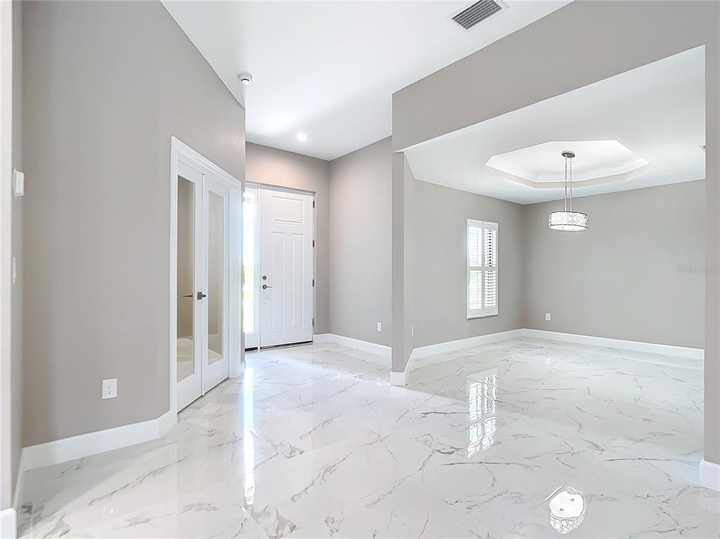 A bright foyer and dining area feature light gray walls and polished white marble flooring — 14267 MONTMARTE AVENUE, PORT CHARLOTTE, FL