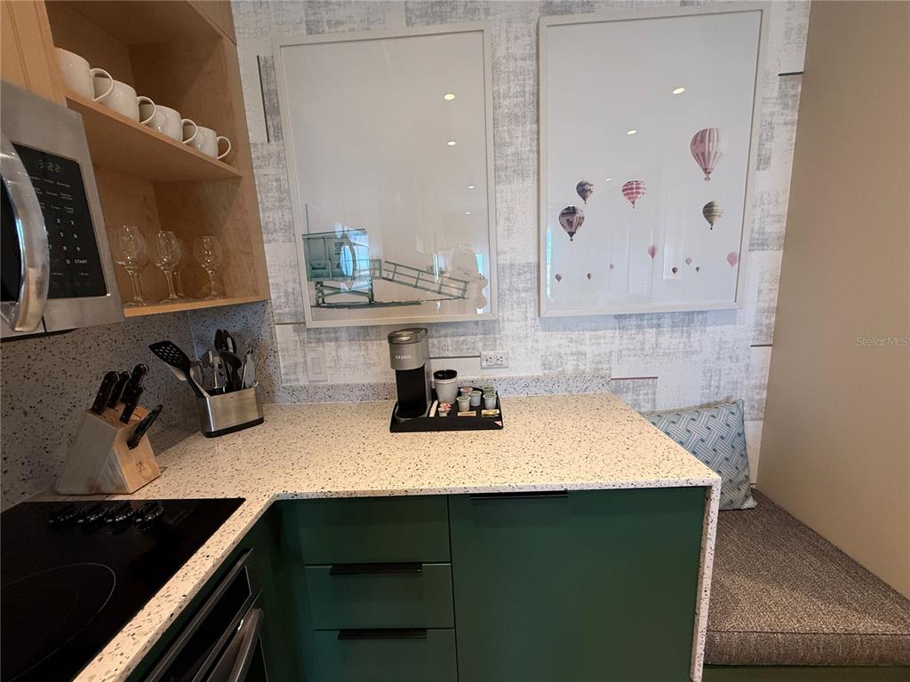 A kitchen features green cabinets, speckled countertops, a coffee station, and framed wall art — 3151 SUNSET WALK DRIVE UNIT 212, KISSIMMEE, FL