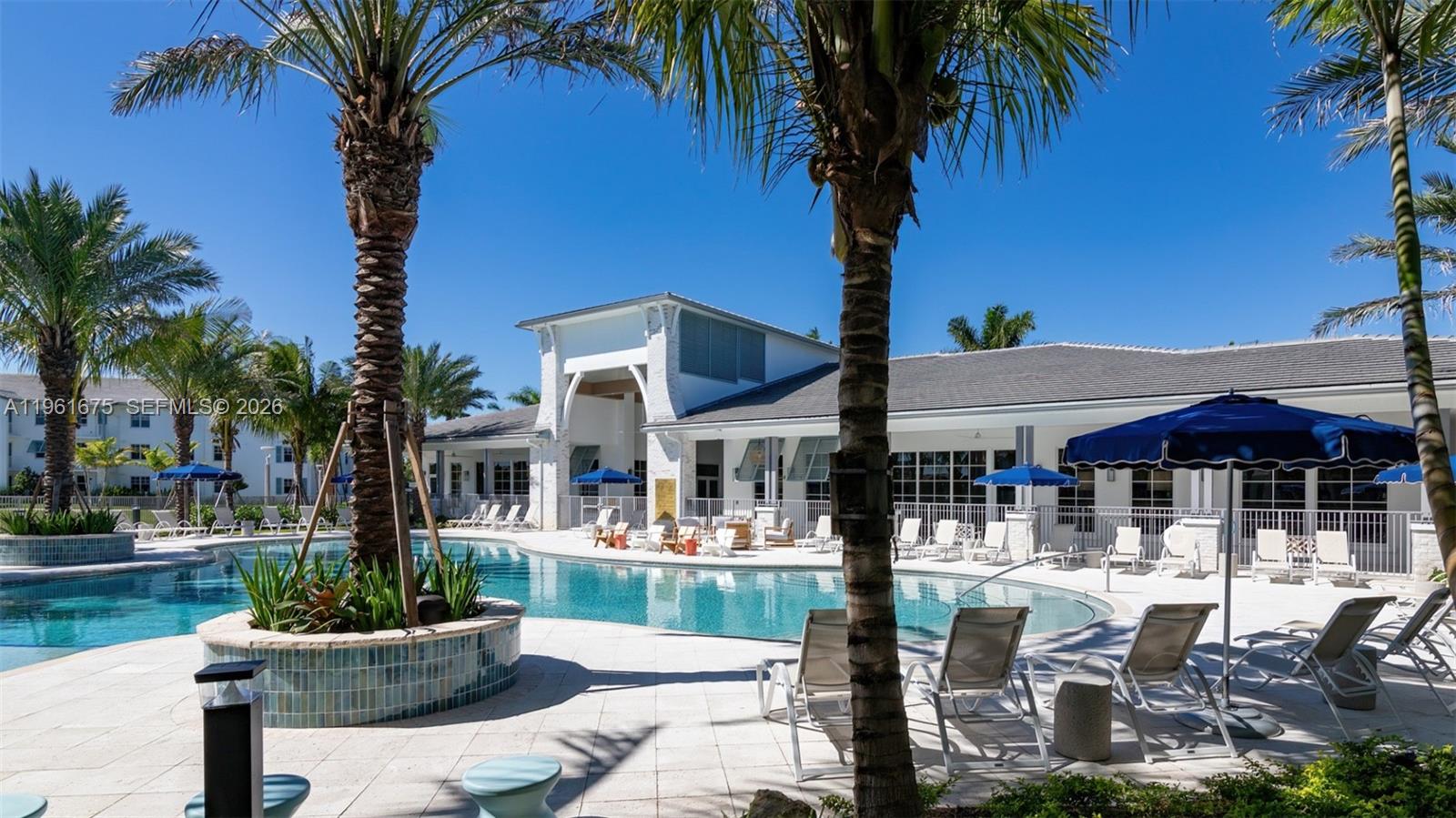 A swimming pool with lounge chairs sits in front of a white clubhouse building — 4310 Chukka Ln # B1, Lake Worth FL 33467, LAKE WORTH, FL