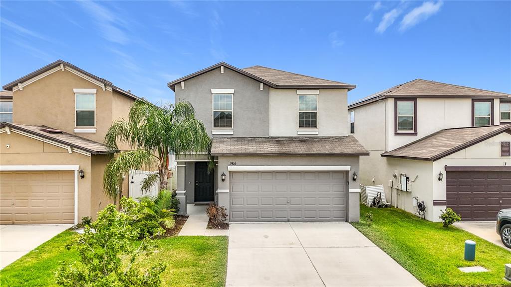 A two-story suburban house with a gray facade, a two-car garage, and a palm tree — 7405 EVENING PRIMROSE COURT, TAMPA, FL