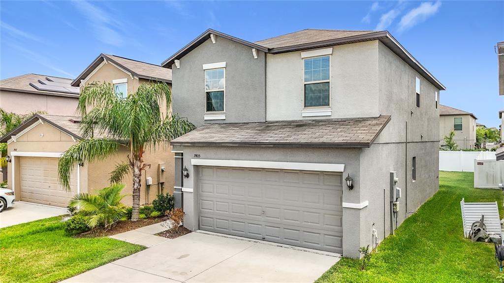 A two-story gray stucco house with a two-car garage and a palm tree in front — 7405 EVENING PRIMROSE COURT, TAMPA, FL