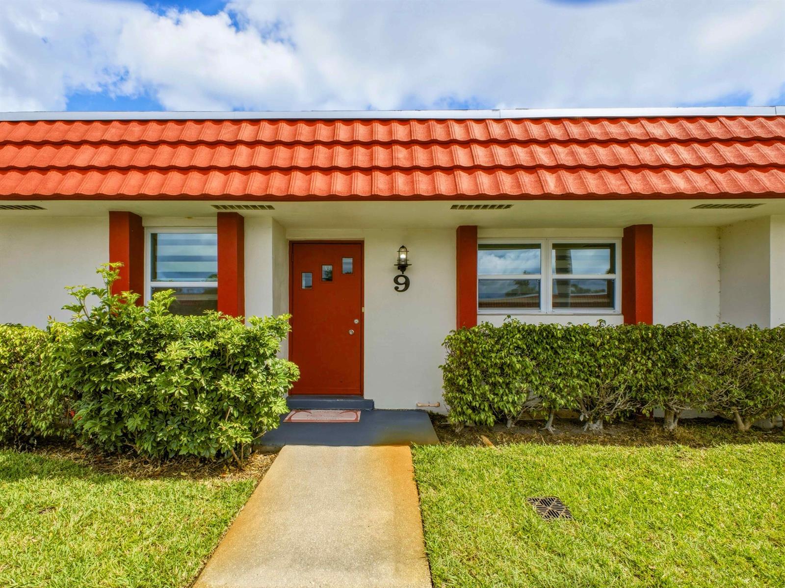 A single-story house exterior features a red tile roof, white walls, and a red door — 5800 W Fernley Dr W # 9, FL 33415, FL
