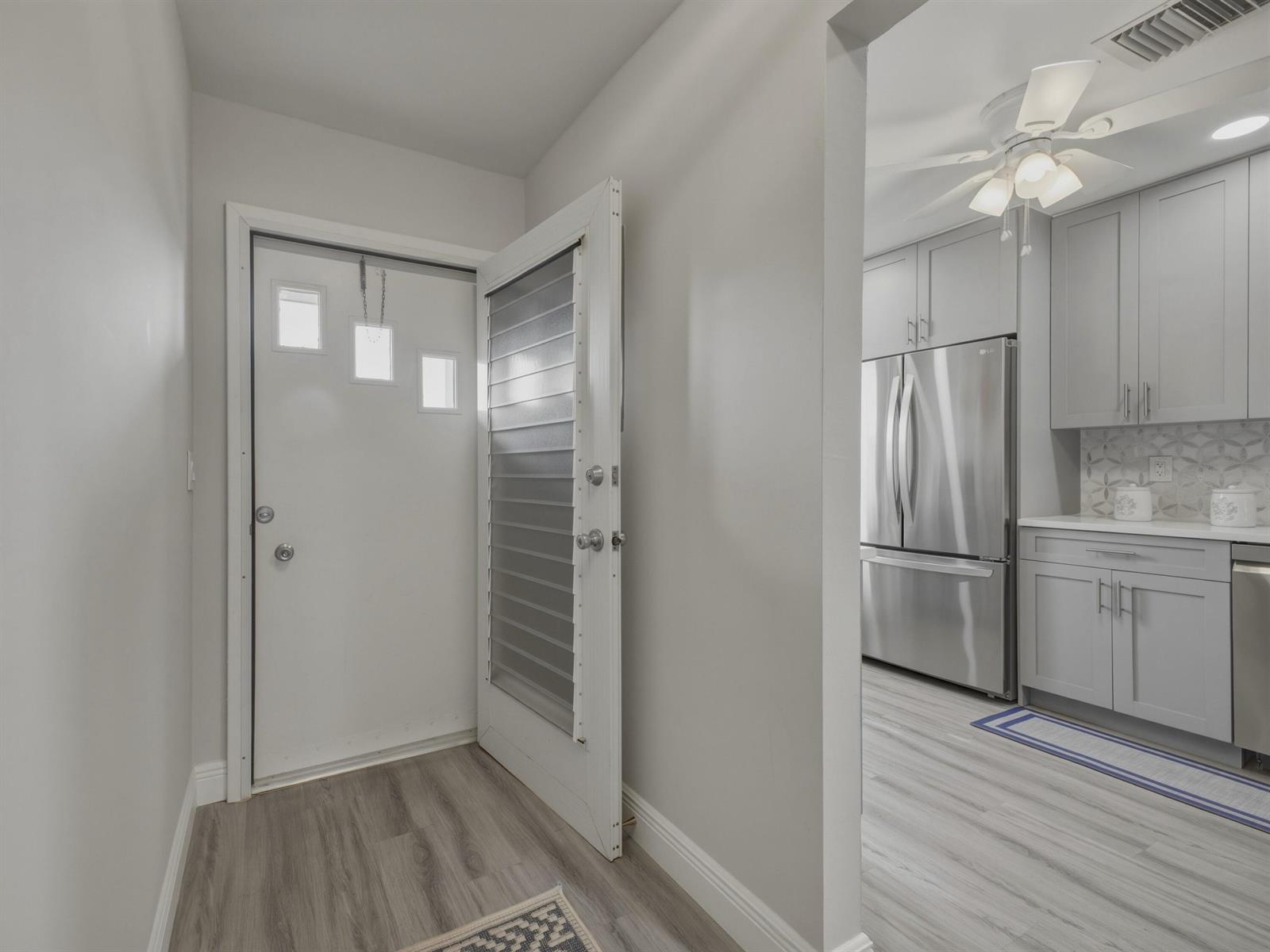 An entryway with a white door opens into a kitchen featuring gray cabinets and appliances — 5800 W Fernley Dr W # 9, FL 33415, FL