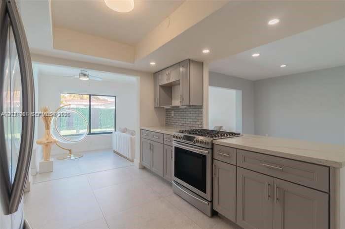 A kitchen with gray cabinets, stainless steel appliances, and a view into a sunlit room — 8531 NW 25th St, Sunrise FL 33322, SUNRISE, FL