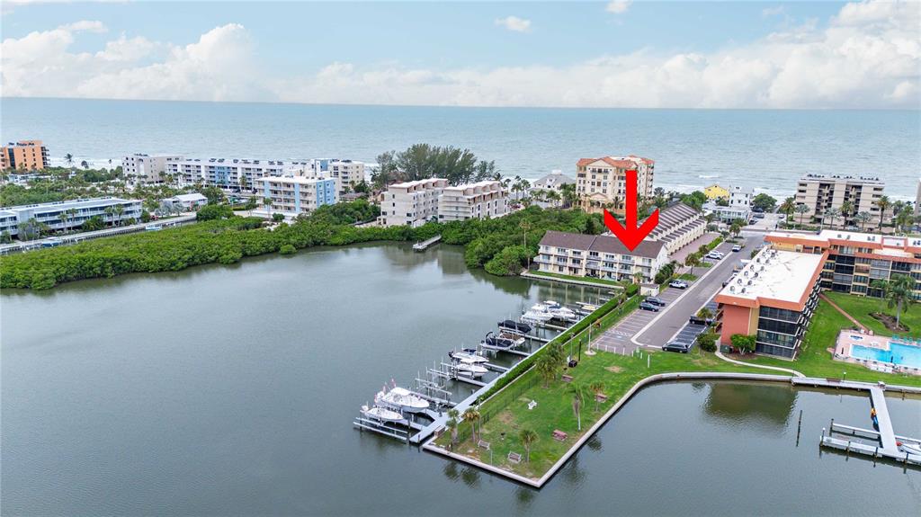 An aerial view shows a waterfront condominium complex with a marina and boat slips — 19651 GULF BOULEVARD UNIT B2, INDIAN SHORES, FL