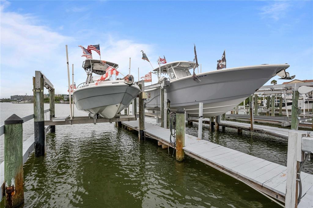 Two boats are lifted on a wooden dock system over a body of water — 19651 GULF BOULEVARD UNIT B2, INDIAN SHORES, FL
