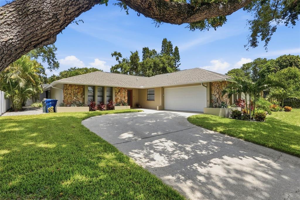 A single-story house with a stone facade, a two-car garage, and a curved concrete driveway — 707 KNOLLWOOD DRIVE, LARGO, FL