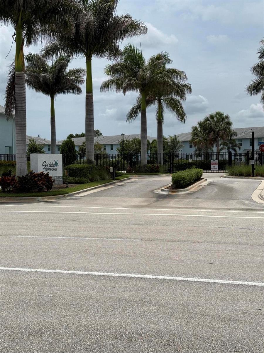 The entrance to Seaside Townhomes features a gated driveway lined with tall palm trees — 342 SE Angler Drive, Stuart FL 34994, STUART, FL
