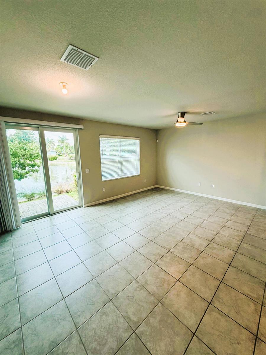 An empty room with tile flooring, a ceiling fan, and a sliding glass door view — 342 SE Angler Drive, Stuart FL 34994, STUART, FL