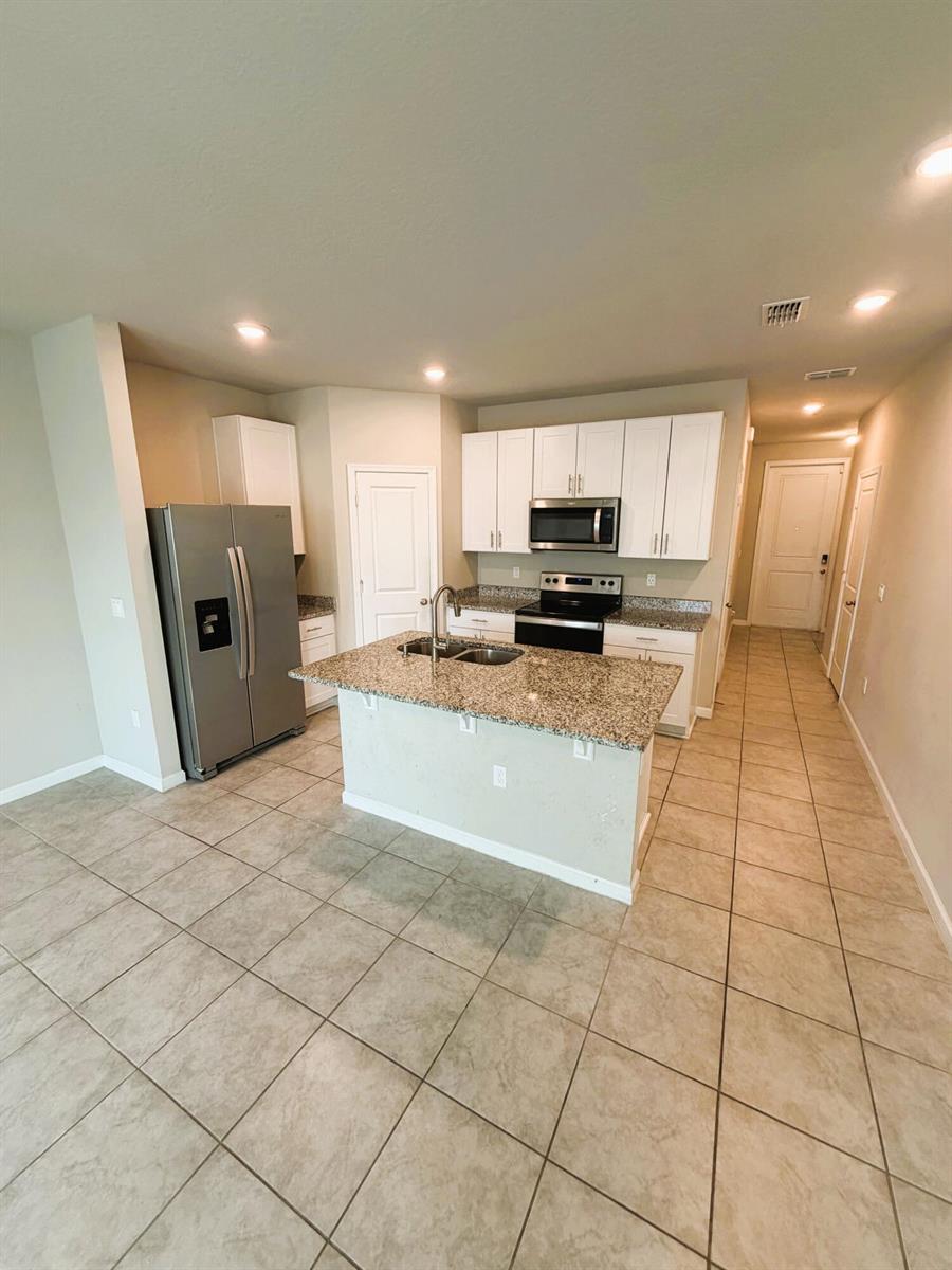 A kitchen features white cabinets, granite countertops, a center island, and stainless steel appliances — 342 SE Angler Drive, Stuart FL 34994, STUART, FL