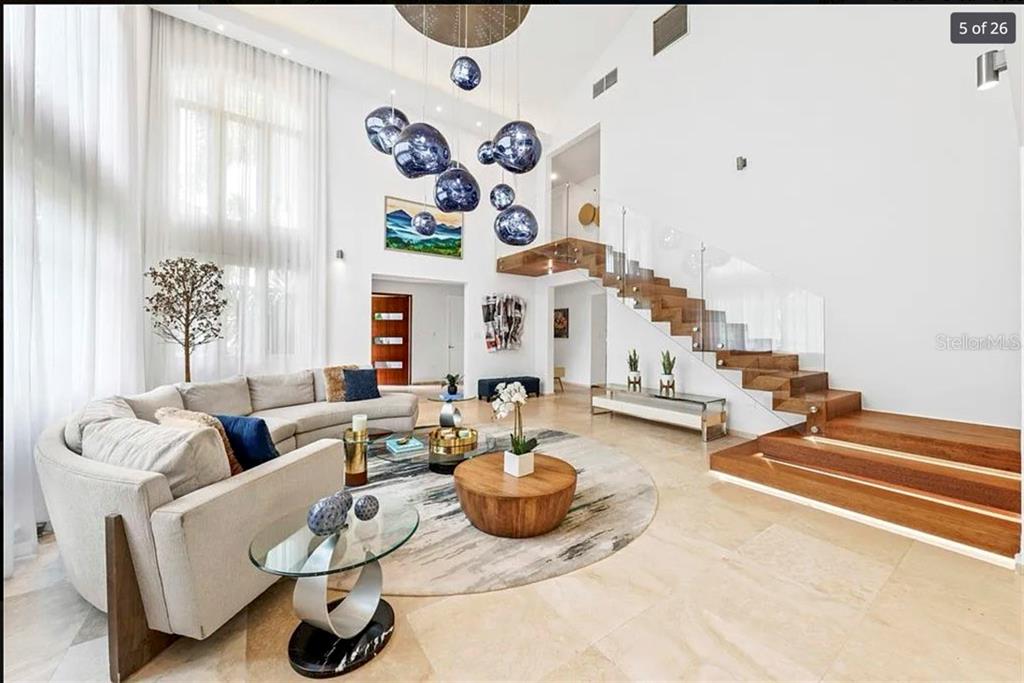 A modern living room features a floating staircase, a large sectional sofa, and pendant lighting — 121 DORADO BEACH EAST, DORADO, PR
