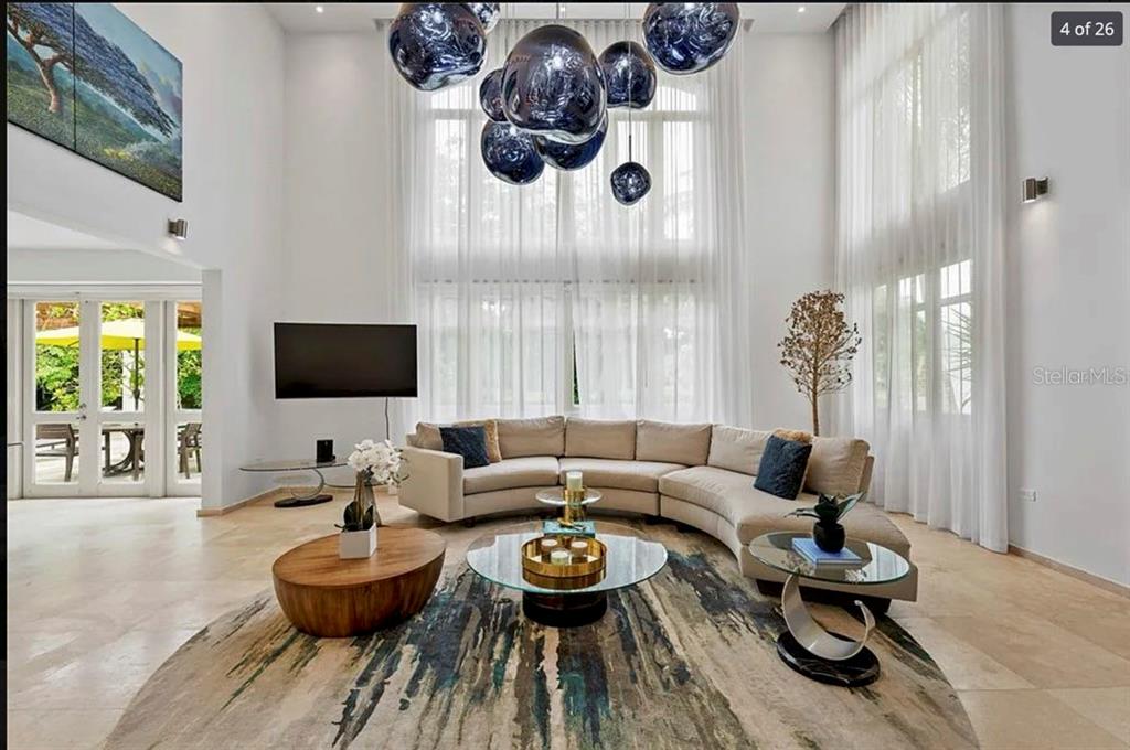 A living room features a curved sectional sofa, a large area rug, and a modern chandelier — 121 DORADO BEACH EAST, DORADO, PR