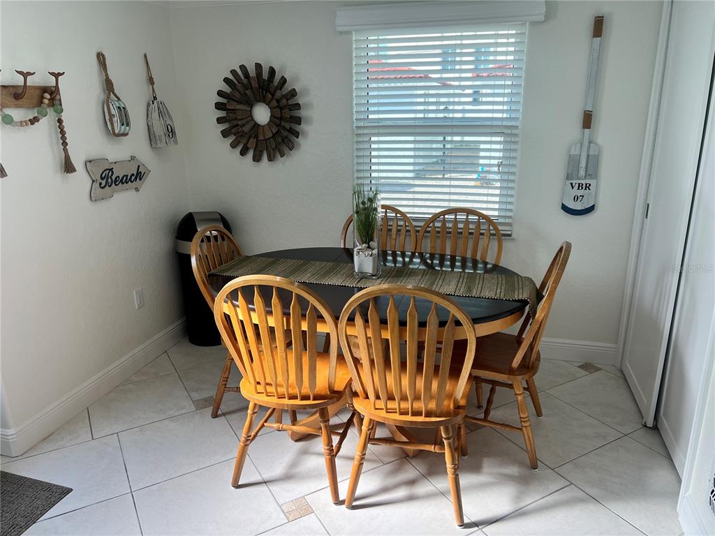 A dining area features a dark oval table with wooden chairs and coastal wall decor — 6154 MIDNIGHT PASS ROAD UNIT B16, SARASOTA, FL