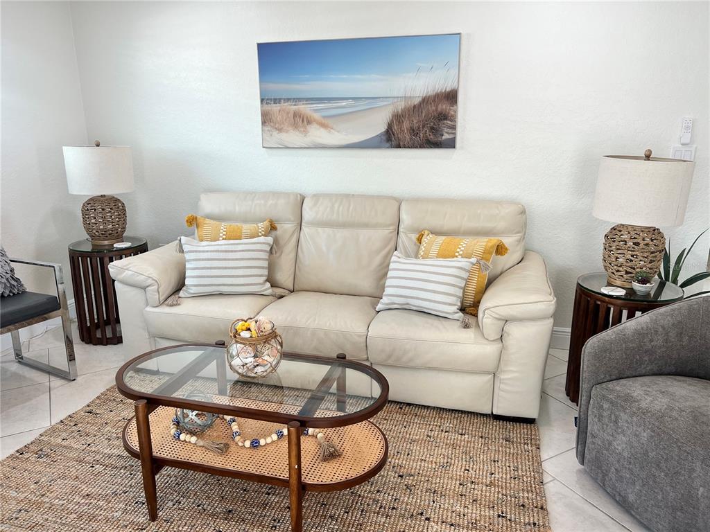 A living room features a beige leather sofa, a glass coffee table, and coastal decor — 6154 MIDNIGHT PASS ROAD UNIT B16, SARASOTA, FL