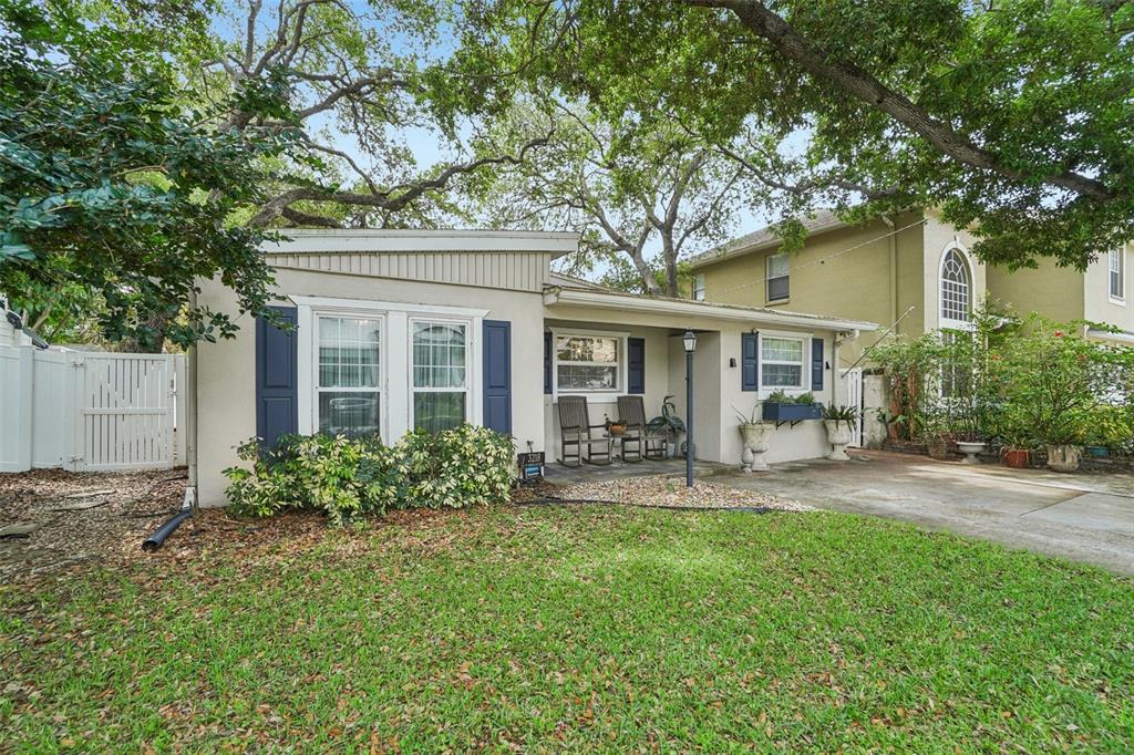A single-story house with a covered front porch, blue shutters, and a large oak tree — 3218 W OAKELLAR AVENUE, TAMPA, FL