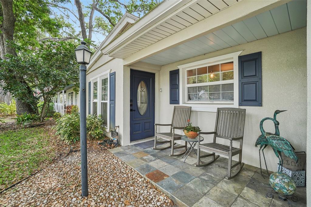 A front porch with slate tile flooring, two rocking chairs, and a blue front door — 3218 W OAKELLAR AVENUE, TAMPA, FL
