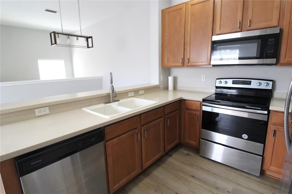 A kitchen features wood cabinets, stainless steel appliances, a white sink, and light countertops — 3475 PARKRIDGE CIRCLE UNIT 17-202, SARASOTA, FL