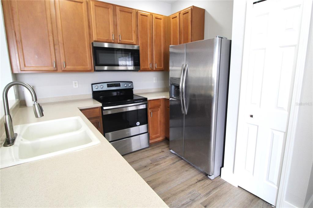 A kitchen features wood cabinets, stainless steel appliances, a double sink, and light-colored countertops — 3475 PARKRIDGE CIRCLE UNIT 17-202, SARASOTA, FL