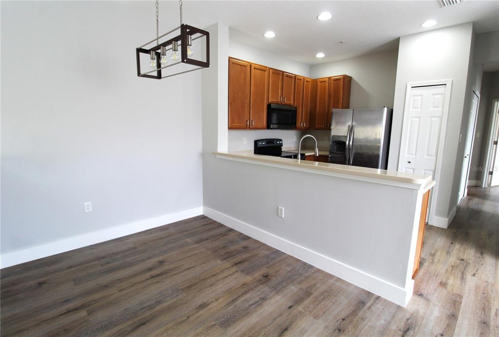 A kitchen with wood cabinets and stainless steel appliances overlooks a dining area with flooring — 3475 PARKRIDGE CIRCLE UNIT 17-202, SARASOTA, FL