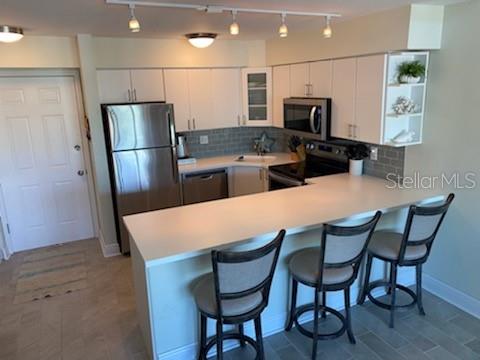 A kitchen features white cabinets, stainless steel appliances, a breakfast bar, and three bar stools — 2400 S OCEAN DRIVE UNIT 5331, FORT PIERCE, FL