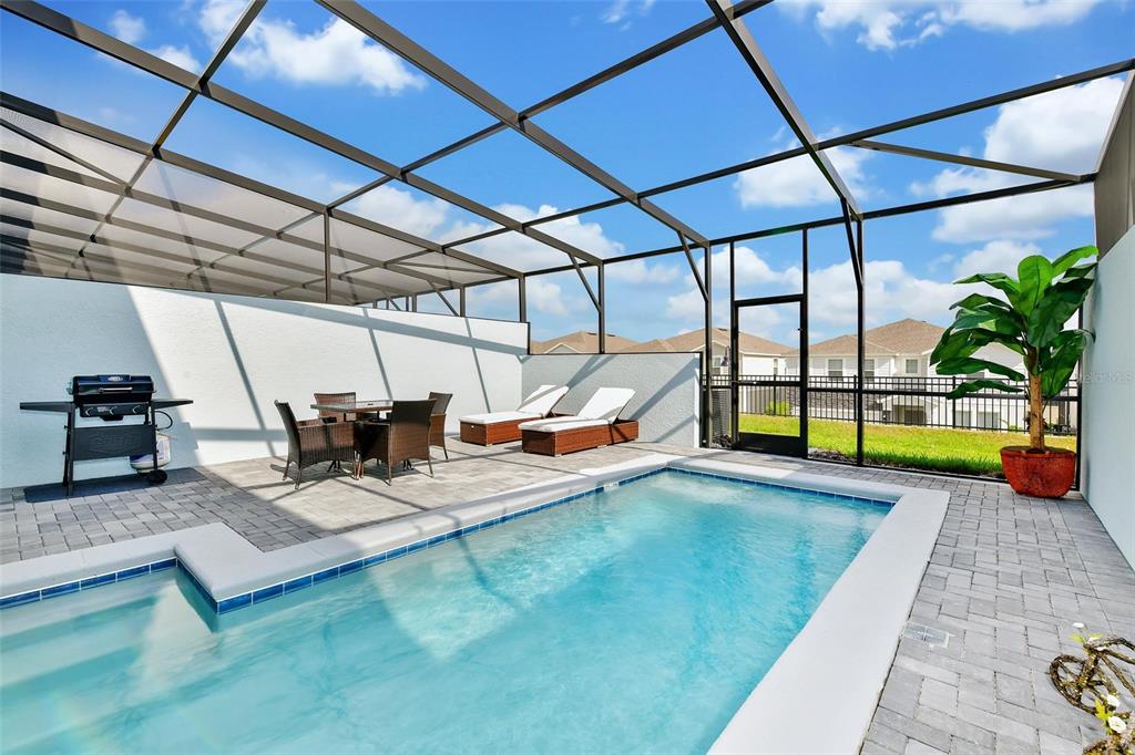 A screened-in patio features a rectangular swimming pool, outdoor dining set, and lounge chairs — 3721 PACIFIC LANE, DAVENPORT, FL