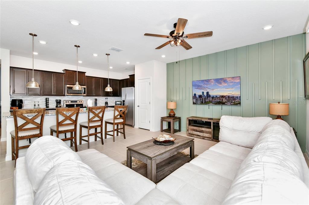 An open-concept living room and kitchen featuring a light green accent wall and wood furniture — 3721 PACIFIC LANE, DAVENPORT, FL