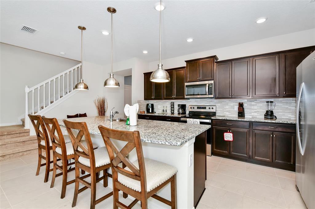 A kitchen with dark wood cabinets, granite countertops, a center island, and bar stool seating — 3721 PACIFIC LANE, DAVENPORT, FL