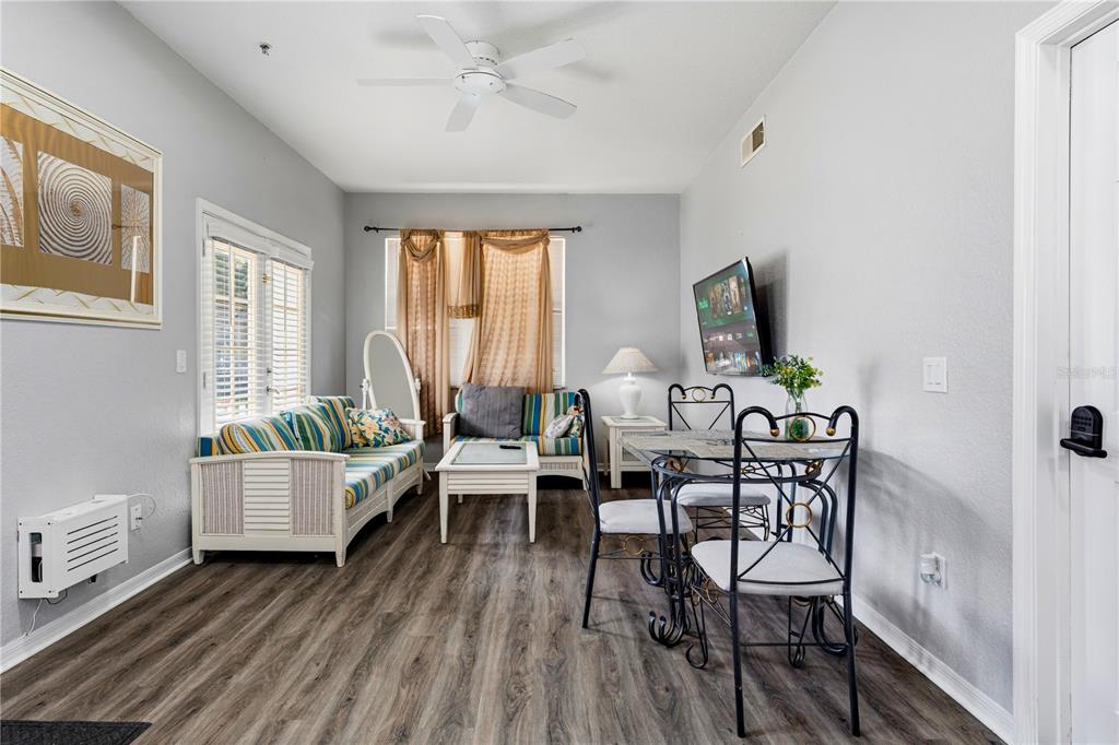 A living and dining area features wood-look flooring, a ceiling fan, and white wicker furniture — 4006 SAN GALLO DRIVE UNIT 108, KISSIMMEE, FL