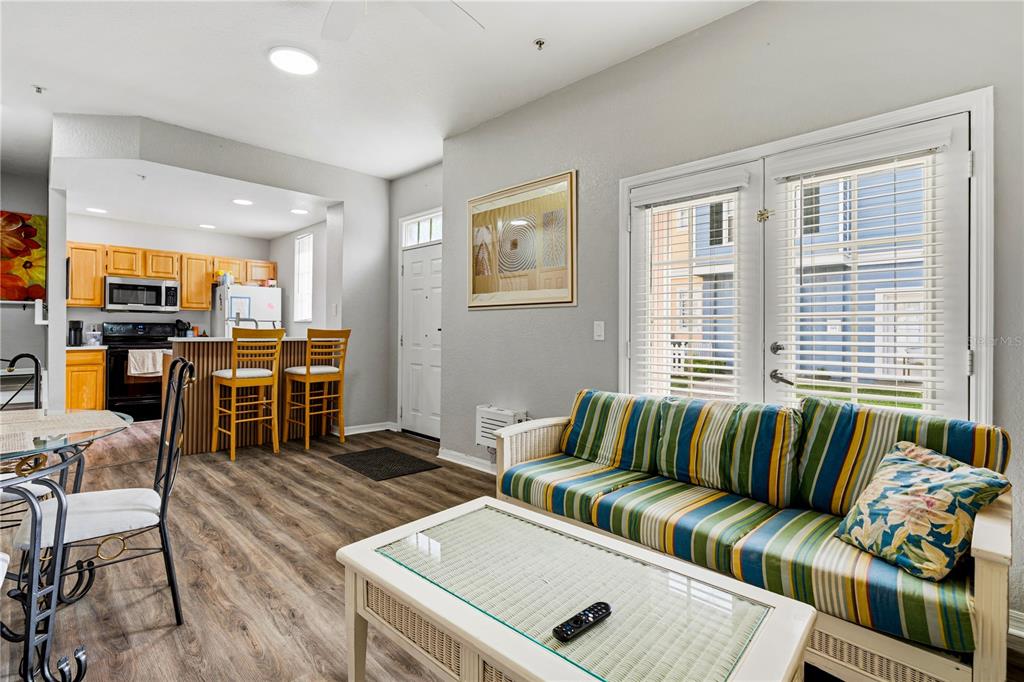 A living room with a striped sofa and a kitchen with wooden cabinets and bar stools — 4006 SAN GALLO DRIVE UNIT 108, KISSIMMEE, FL