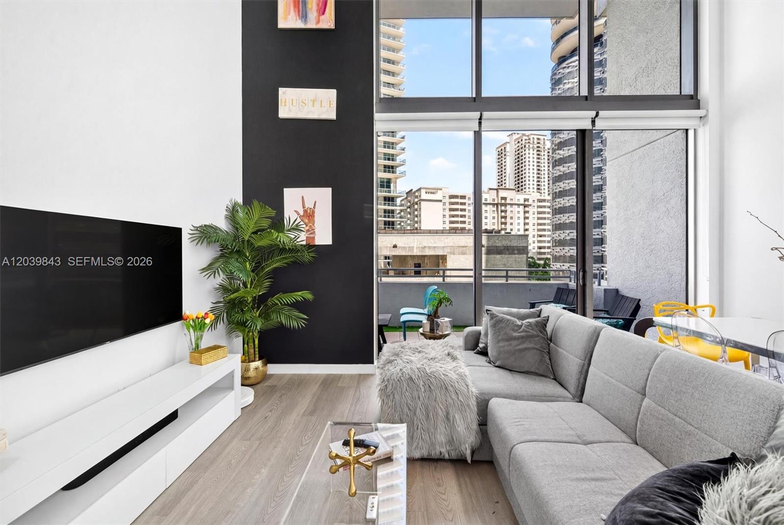 A modern living room features a gray sectional sofa, black accent wall, and floor-to-ceiling windows — 1050 Brickell Ave # 420, Miami FL 33131, MIAMI, FL