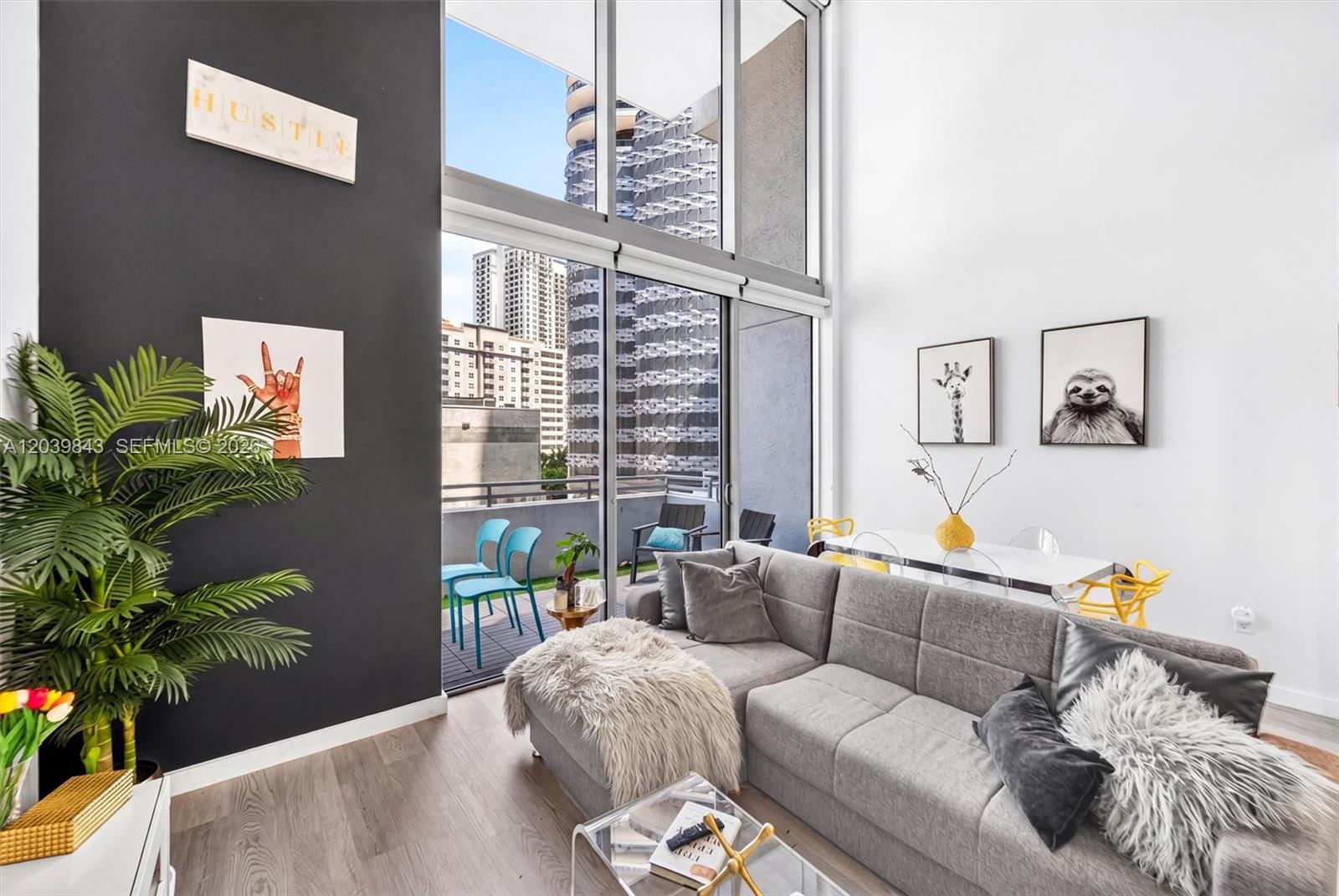 A living room with a grey sectional, high ceilings, floor-to-ceiling windows, and a balcony — 1050 Brickell Ave # 420, Miami FL 33131, MIAMI, FL