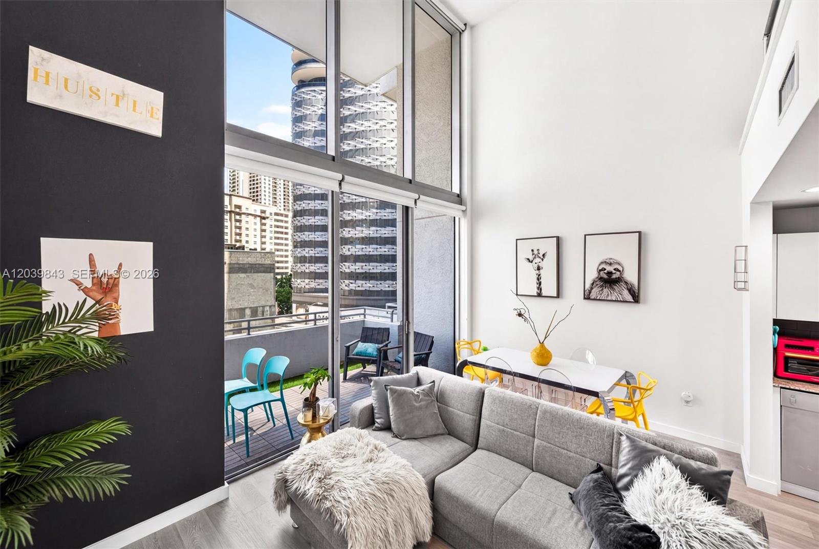 A modern living room features a gray sectional sofa, floor-to-ceiling windows, and a balcony — 1050 Brickell Ave # 420, Miami FL 33131, MIAMI, FL