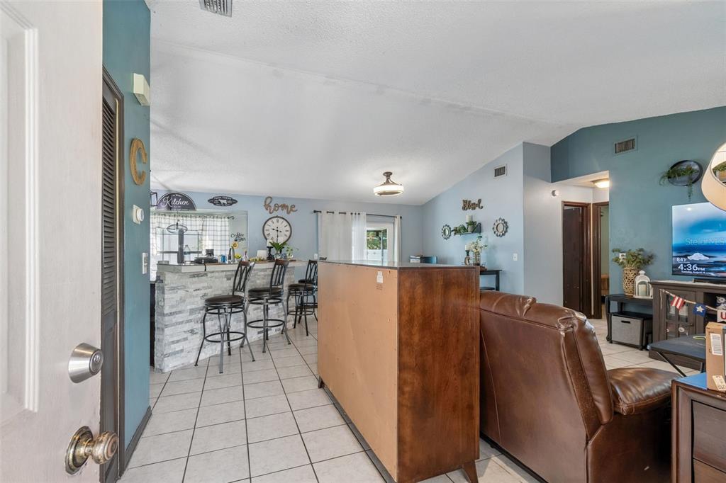 A living room and kitchen area with tile floors, a breakfast bar, and blue walls — 10326 OUT ISLAND DRIVE, TAMPA, FL