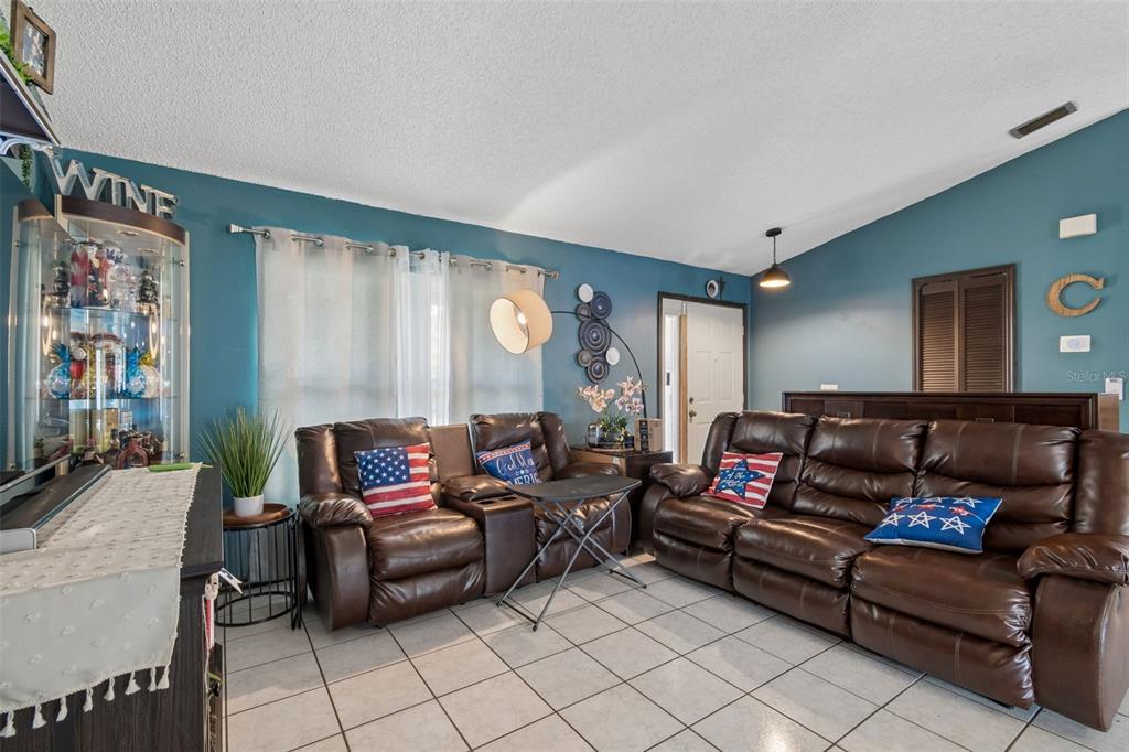 A living room features blue walls, tile flooring, and two brown leather reclining sofas — 10326 OUT ISLAND DRIVE, TAMPA, FL