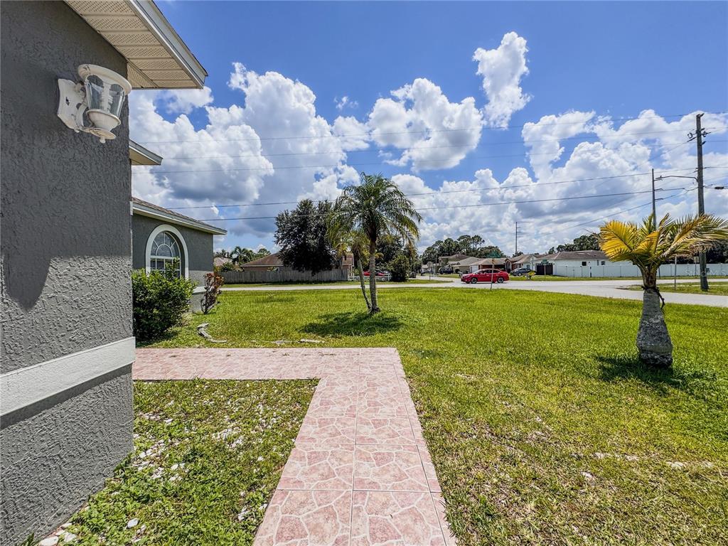 A tiled walkway leads from the side of a house across a grassy front yard — 601 BOBCAT LANE, KISSIMMEE, FL