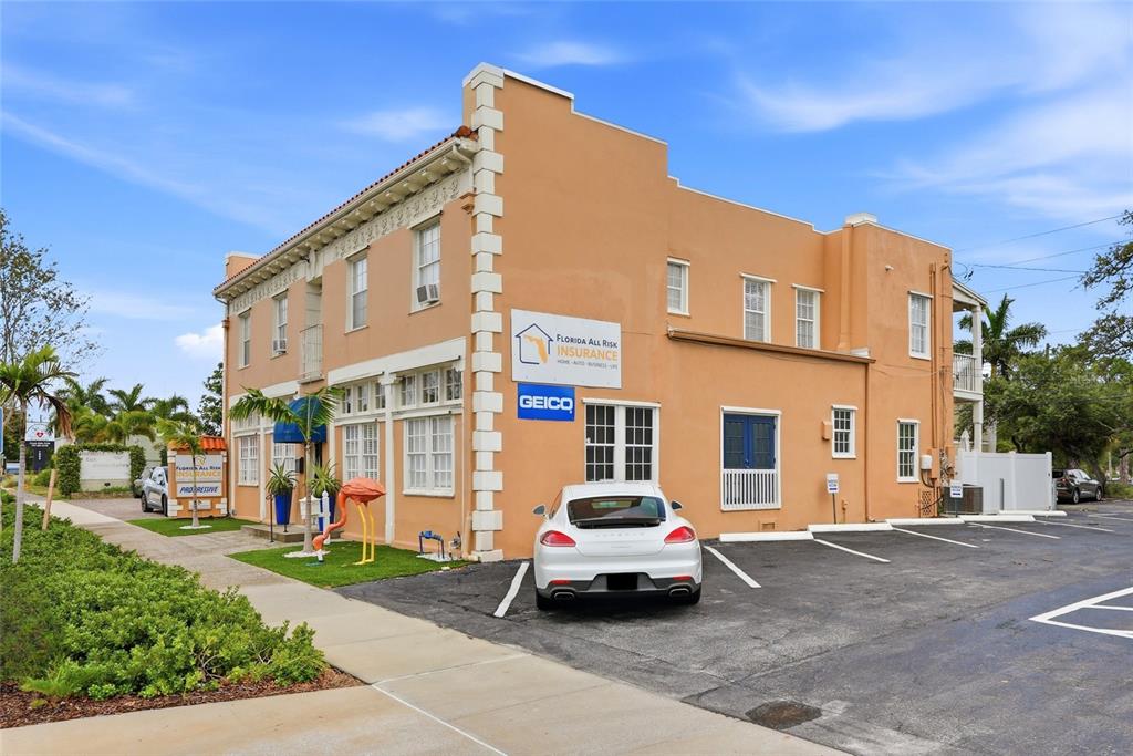 A two-story tan commercial building with a parking lot and a white sports car — 7024 CENTRAL AVENUE, ST PETERSBURG, FL