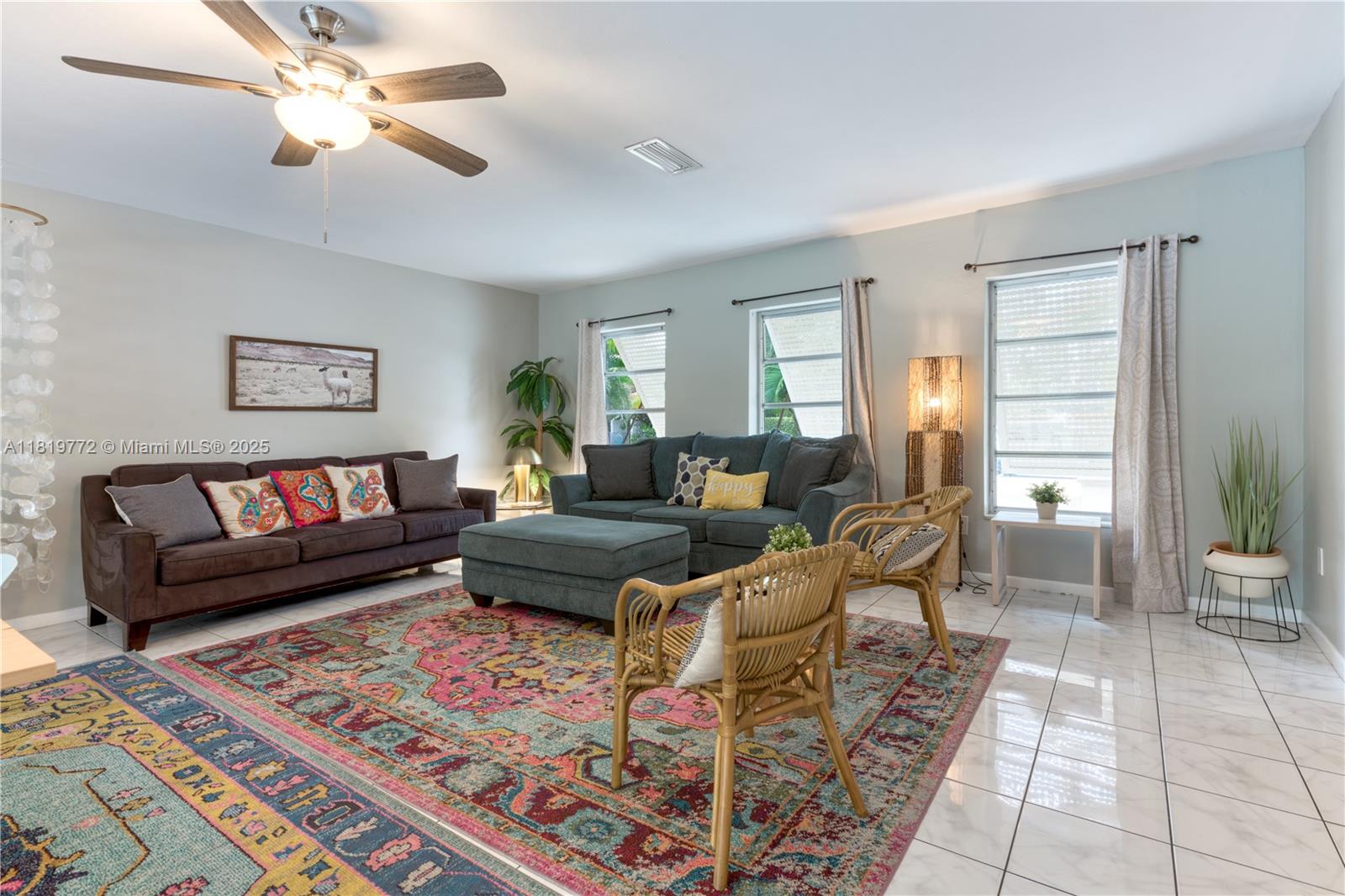 A living room features a colorful area rug, two sofas, rattan chairs, and tile flooring — 1122 S N St, Lake Worth FL 33460, LAKE WORTH, FL