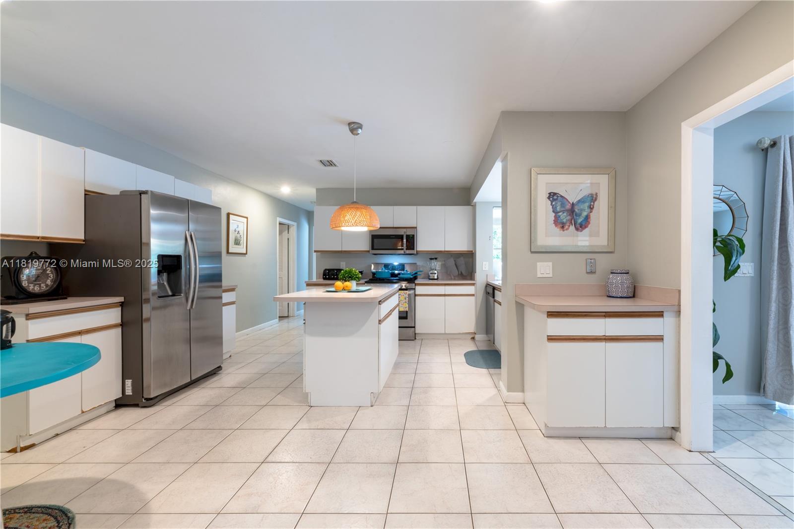 A kitchen features white cabinets, stainless steel appliances, a central island, and light tile flooring — 1122 S N St, Lake Worth FL 33460, LAKE WORTH, FL