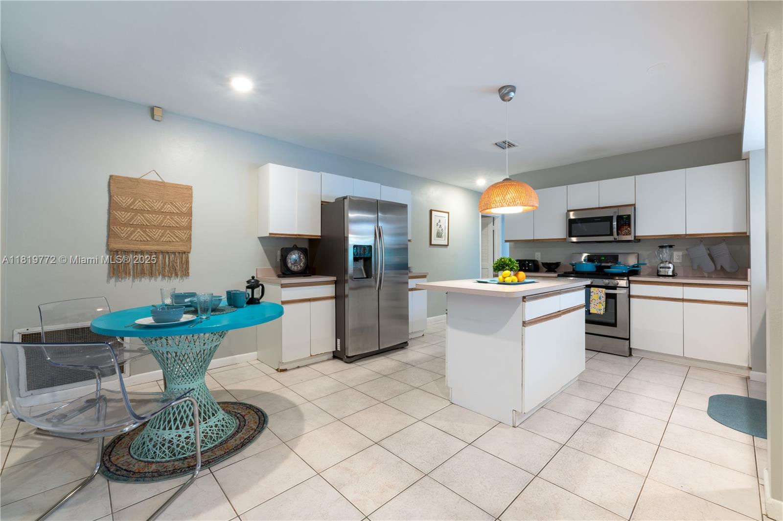 A kitchen features white cabinets, stainless steel appliances, a center island, and a turquoise table — 1122 S N St, Lake Worth FL 33460, LAKE WORTH, FL