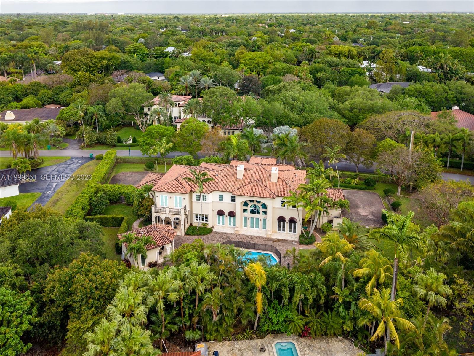 An aerial view shows a large Mediterranean-style house with a tile roof and swimming pool — 12101 Moss Ranch Rd, Pinecrest FL 33156, PINECREST, FL