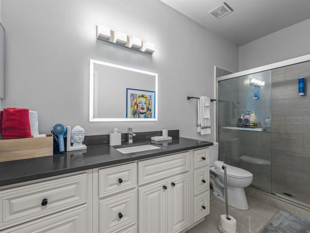 A bathroom features a white vanity with a dark countertop, a lighted mirror, and a shower — 4700 SW ARCHER ROAD UNIT 2, GAINESVILLE, FL