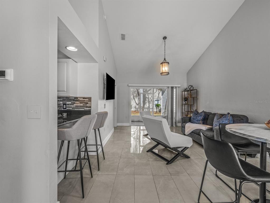 A living room and kitchen area with tile floors, a breakfast bar, and vaulted ceilings — 4700 SW ARCHER ROAD UNIT 2, GAINESVILLE, FL