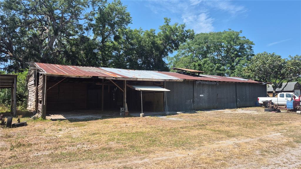 A long, weathered metal-sided barn with an open-front bay sits on a grassy lot — 12858 HIALEAH AVENUE, NEW PORT RICHEY, FL