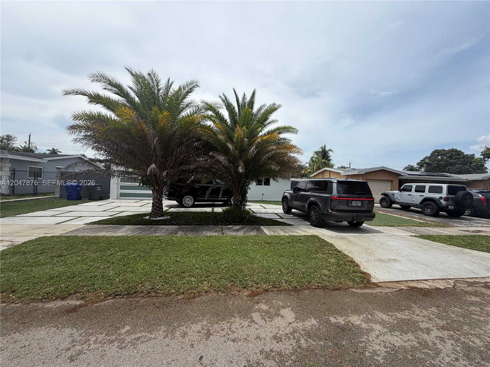 A house exterior features a paved driveway, two palm trees, and several parked vehicles — 7525 Roosevelt St, Hollywood FL 33024, HOLLYWOOD, FL