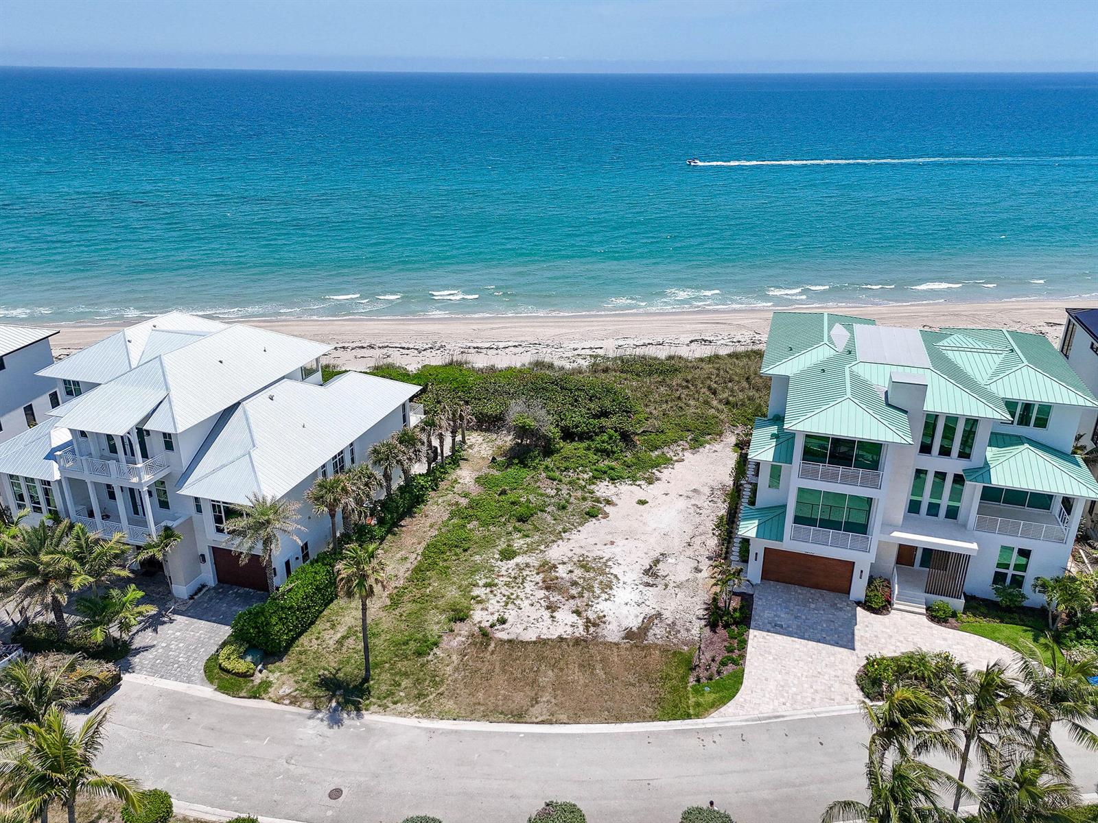 An aerial view shows a vacant beachfront lot situated between two large, multi-story coastal homes — 8128 S Ocean Drive, Jensen Beach FL 34957, JENSEN BEACH, FL