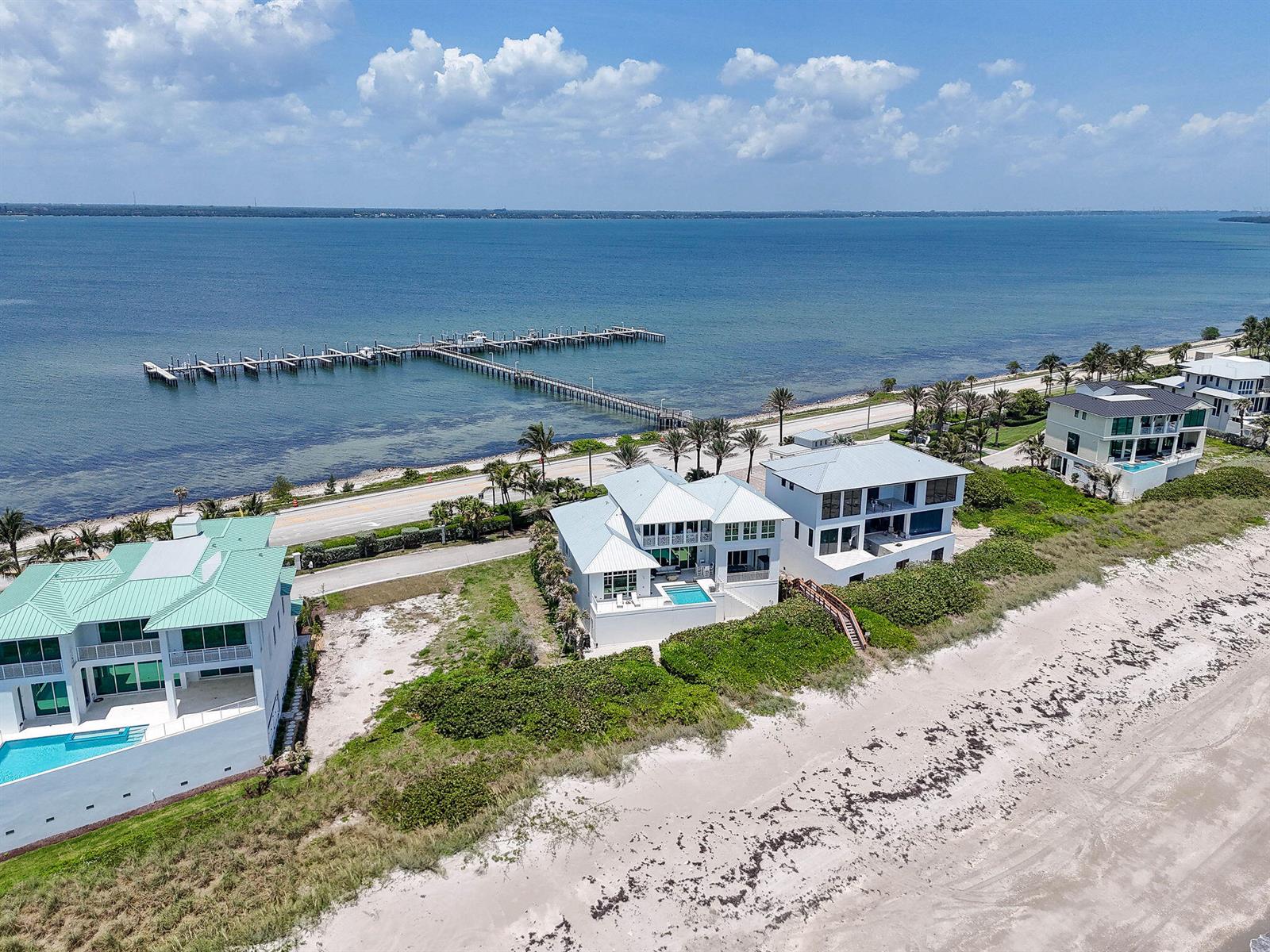 Aerial view of three beachfront houses with pools along a coastal road and pier — 8128 S Ocean Drive, Jensen Beach FL 34957, JENSEN BEACH, FL