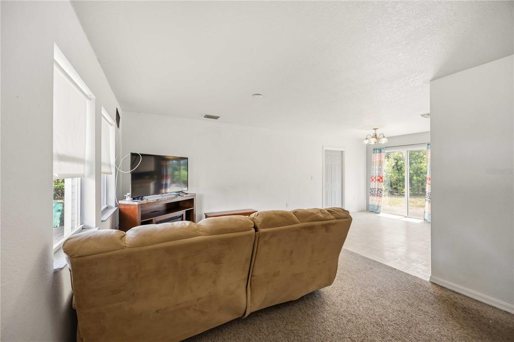 A living room features a tan sofa, a television on a stand, and sliding glass doors — 105 BISCAYNE DRIVE, PORT CHARLOTTE, FL