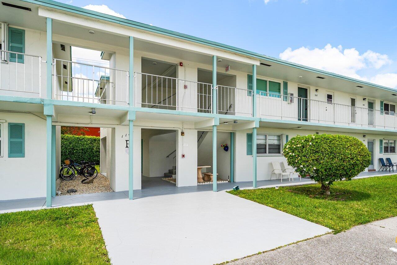 A two-story apartment building features white exterior walls, teal trim, and a concrete walkway — 1117 Lake Terrace # 207, Boynton Beach FL 33426, BOYNTON BEACH, FL
