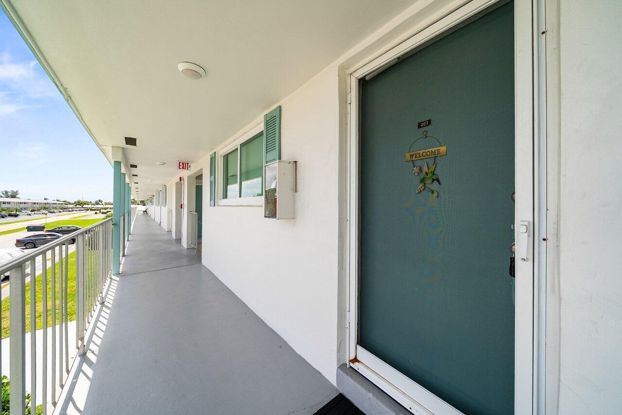An exterior walkway leads to a teal apartment door with a welcome sign — 1117 Lake Terrace # 207, Boynton Beach FL 33426, BOYNTON BEACH, FL